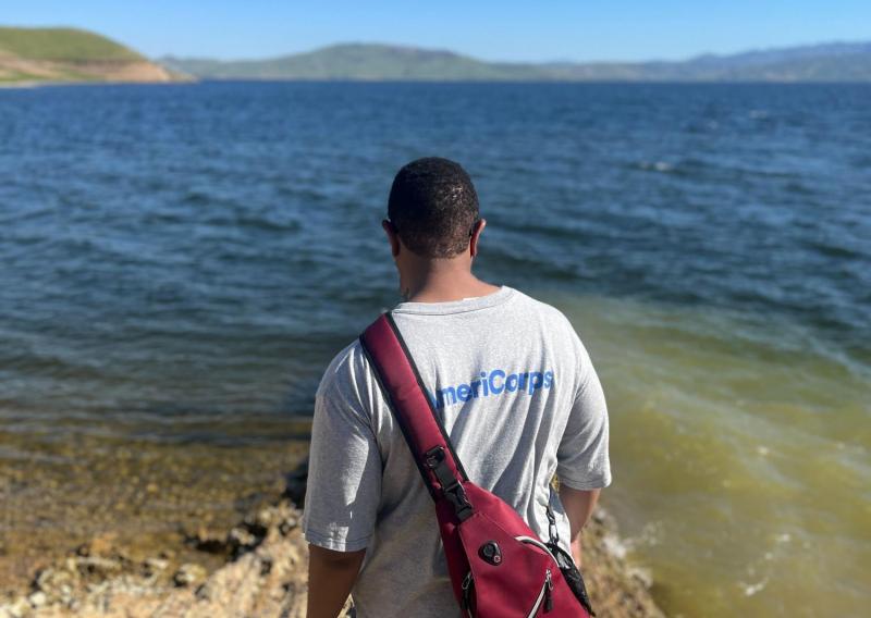 Cameron with AmeriCorps shirt over reservoir