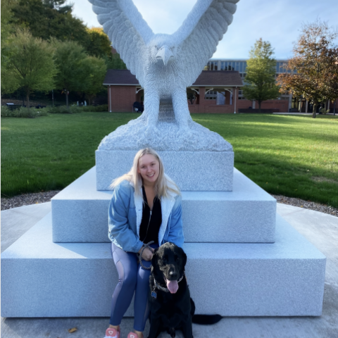 NHC PGH member Laurel smiling in front of a statue with her dog