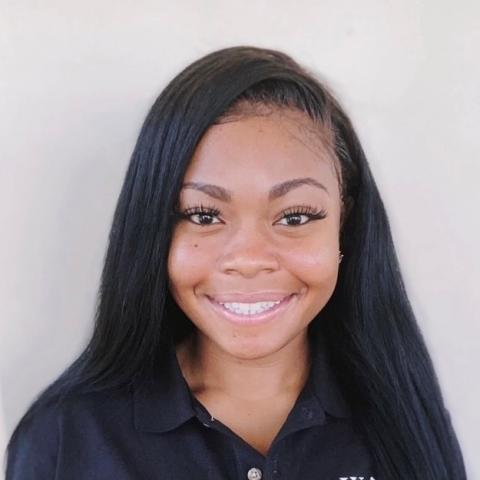 Aliyah smiling for the camera with a black shirt and white background.