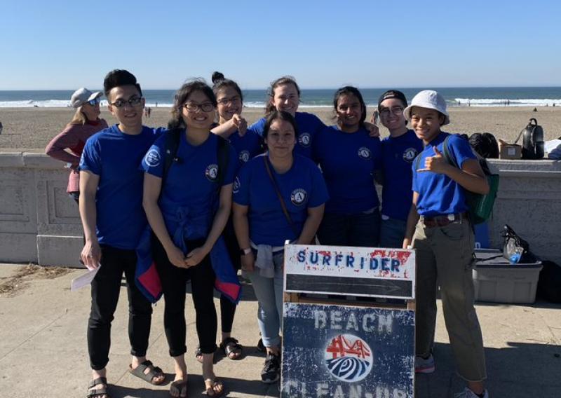 2019-2020 AmeriCorps members standing behind a beach cleanup sign. 