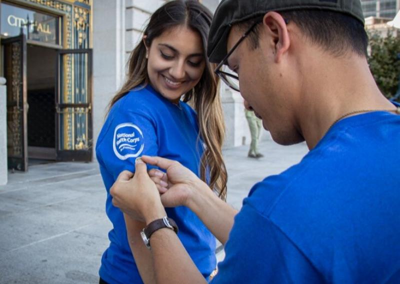 Neha Chhabra receiving her AmeriCorps pin in front of San Francisco City Hall.