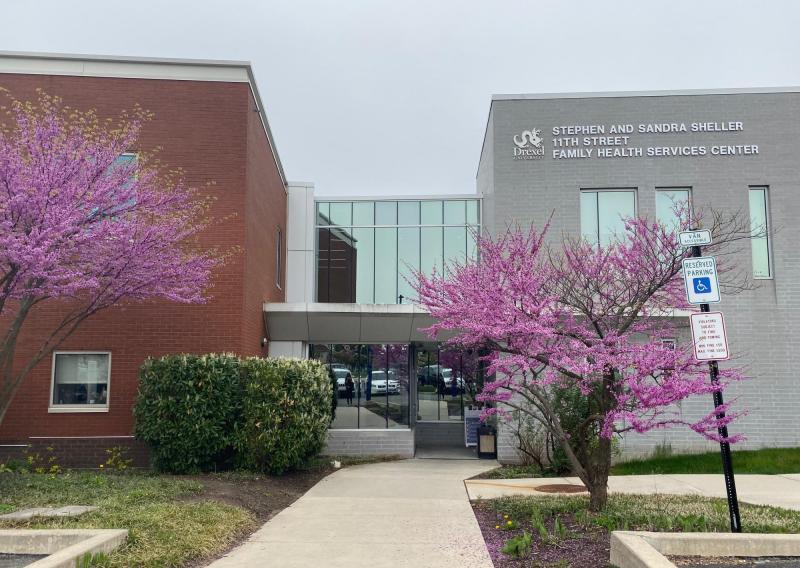 exterior of stephen and sandra sheller 11th street family health services center with two pink trees blooming 