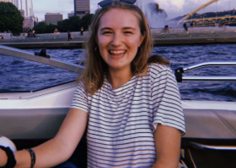 nhc pgh member lexi smiling on a boat with the pittsburgh skyline
