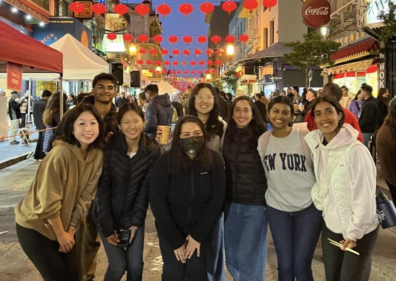 From left to right, members Lilian, Shreyas, Megan, Melanie, Jamie, Laura, Nivedha, Anjalie pose in the center of the frame at the Night Market in Chinatown.