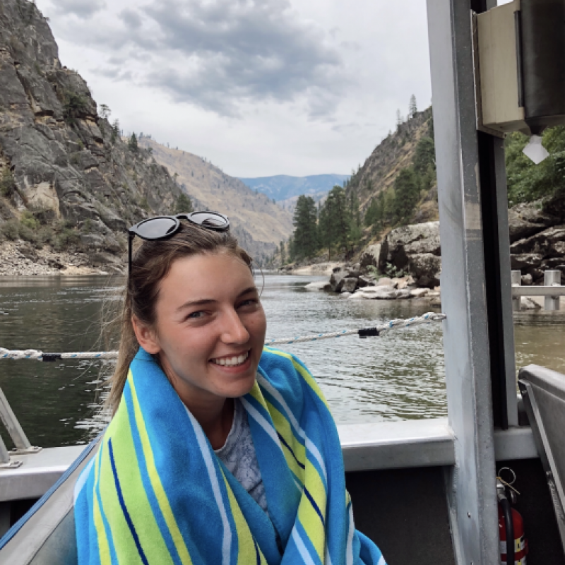 NHC PGH member Victoria smiling on a boat with mountains in the background