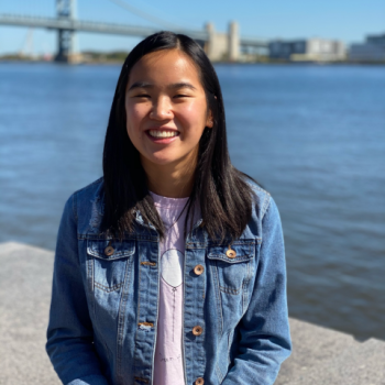 NHC PGH member Lily smiling on a sunny day with a bridge in the background