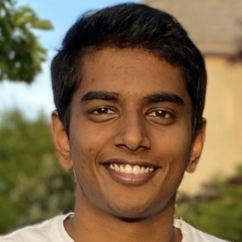 Sai is centered in the frame, facing the camera and smiling. He is wearing a white shirt.