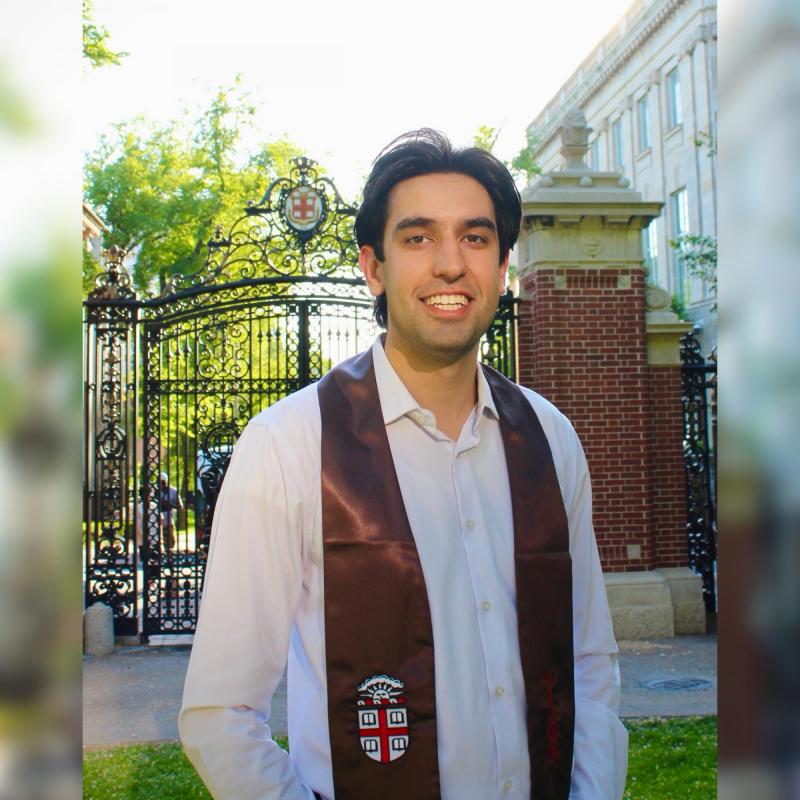 NHC member Kashif Ansari stands with a smile, while wearing a graduation stole.