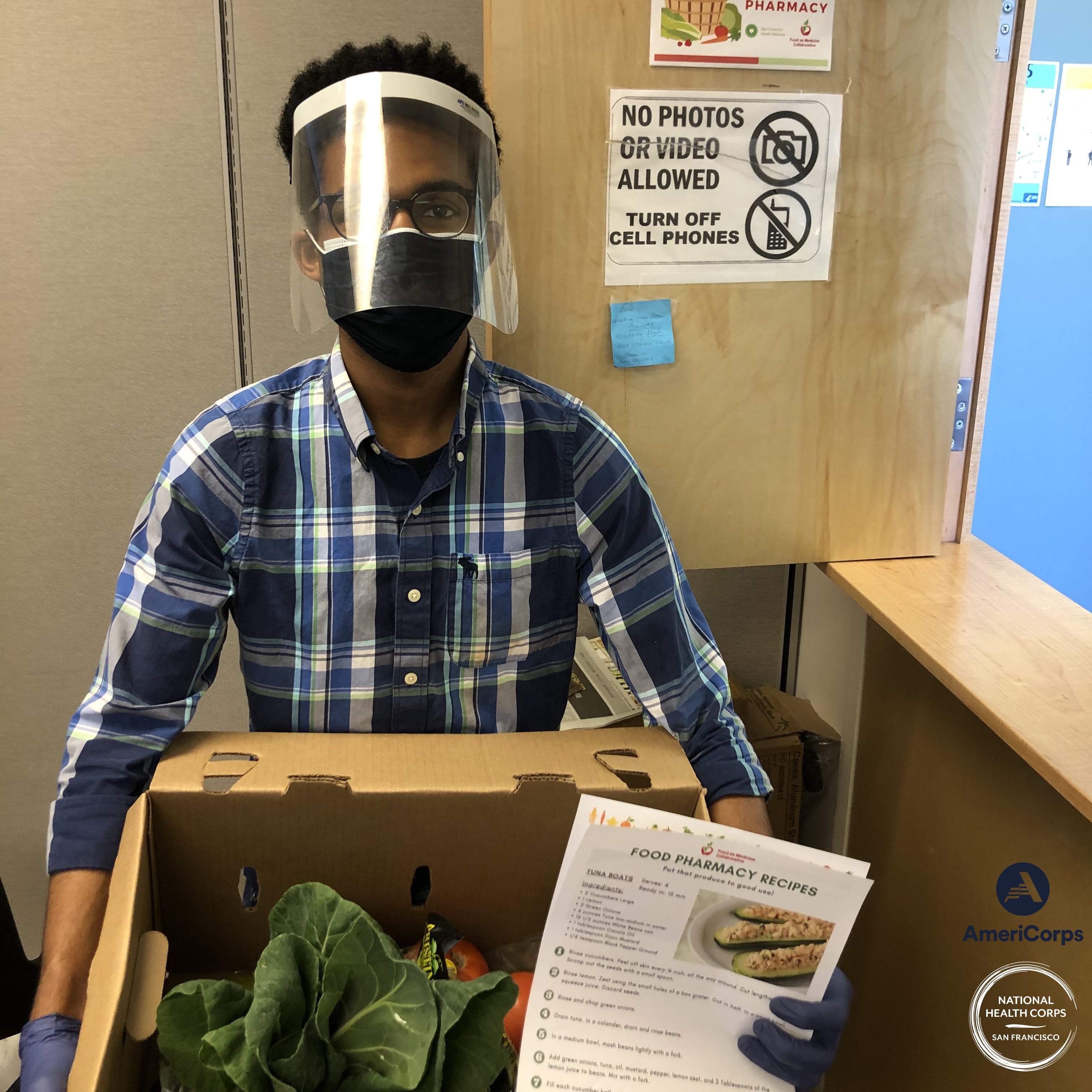 NHC SF member Spencer Robisnon holding a box of produce and a recipe for patients at Food Pharmacy.
