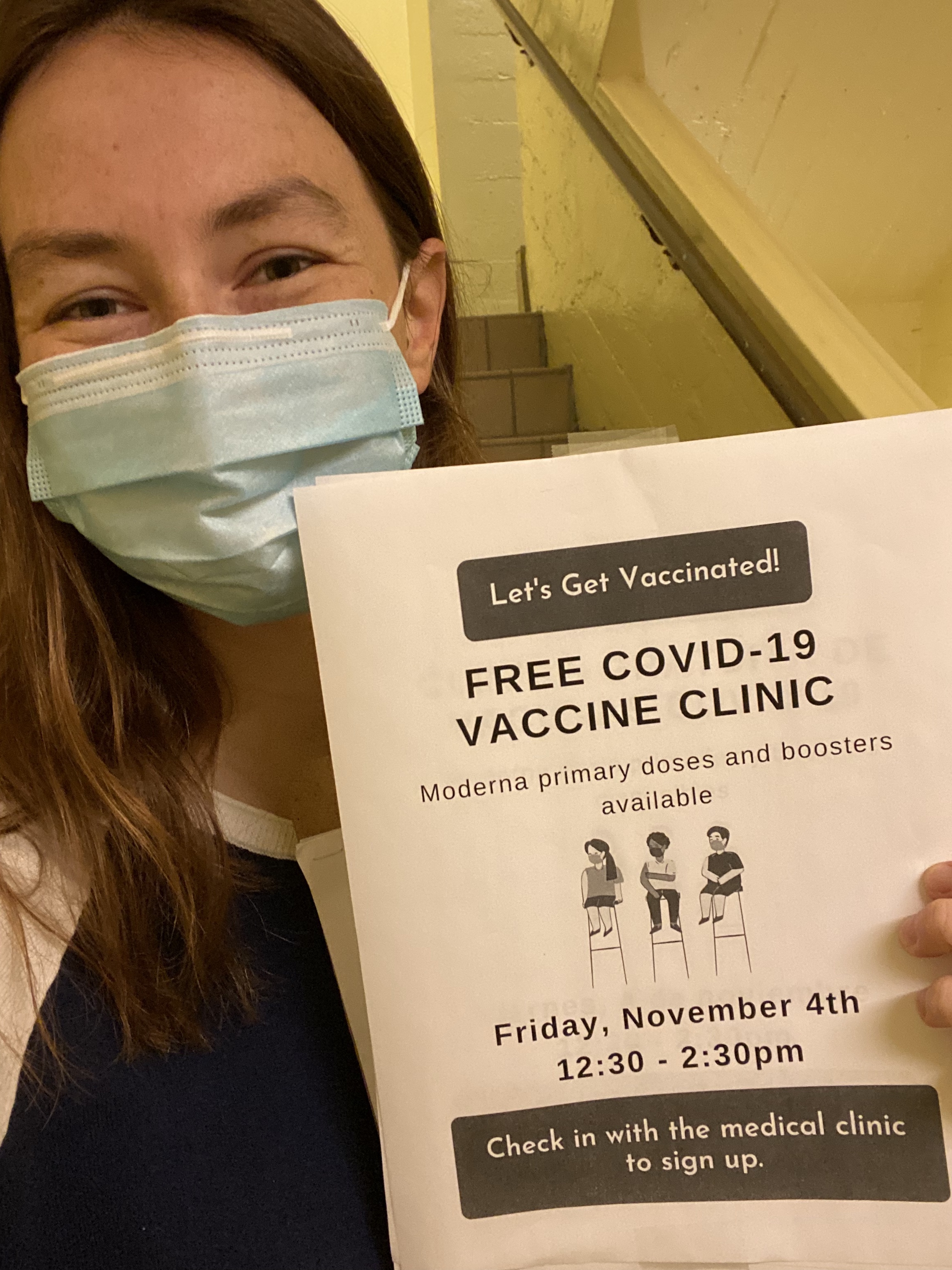 Catherine holding a free vaccination clinic flyer.