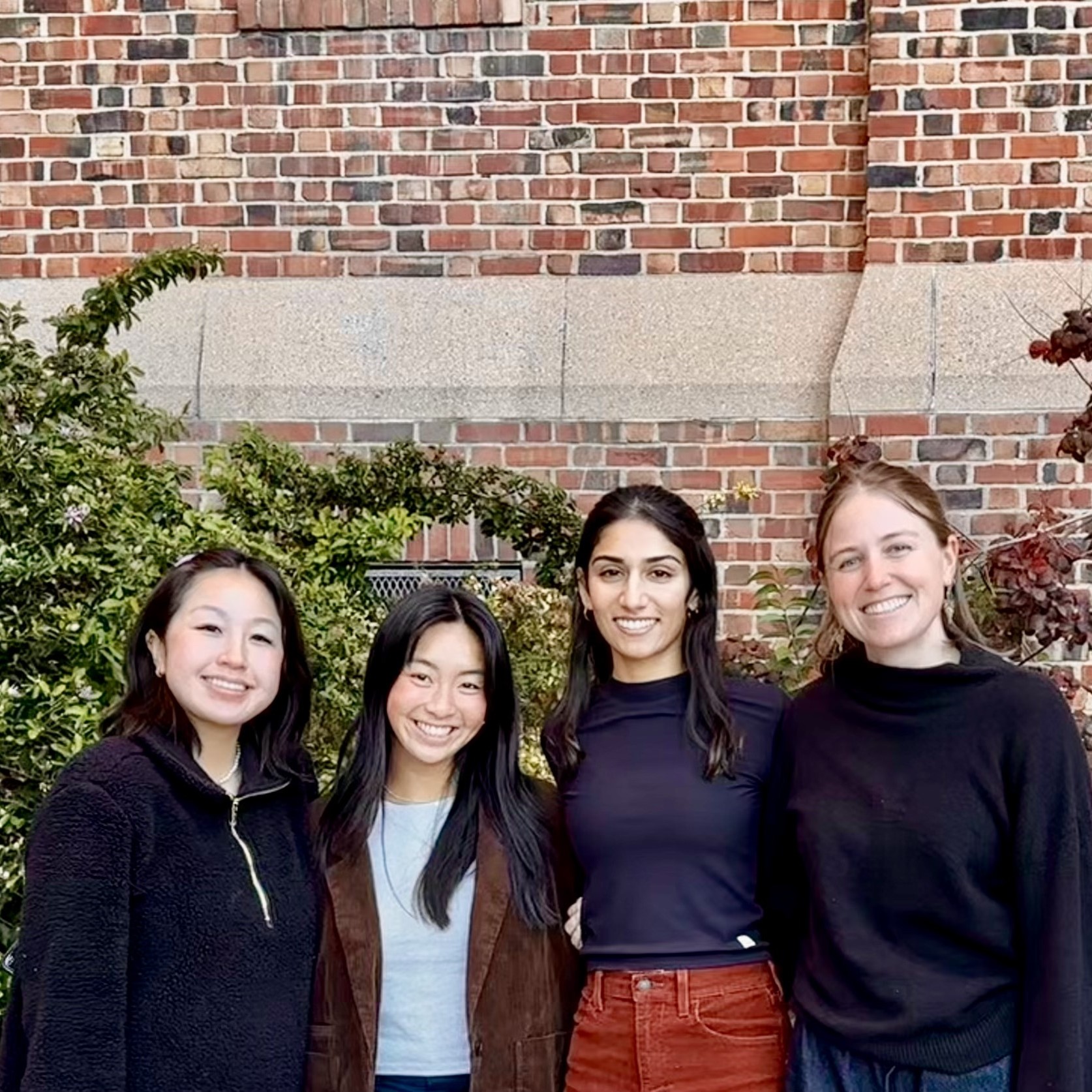 Lilian, Samantha, Anisha, and Morgan stand in the middle of the frame, smiling at the camera. All 4 are Value-Based Care Coordinators focusing on different areas of need at DPH. 