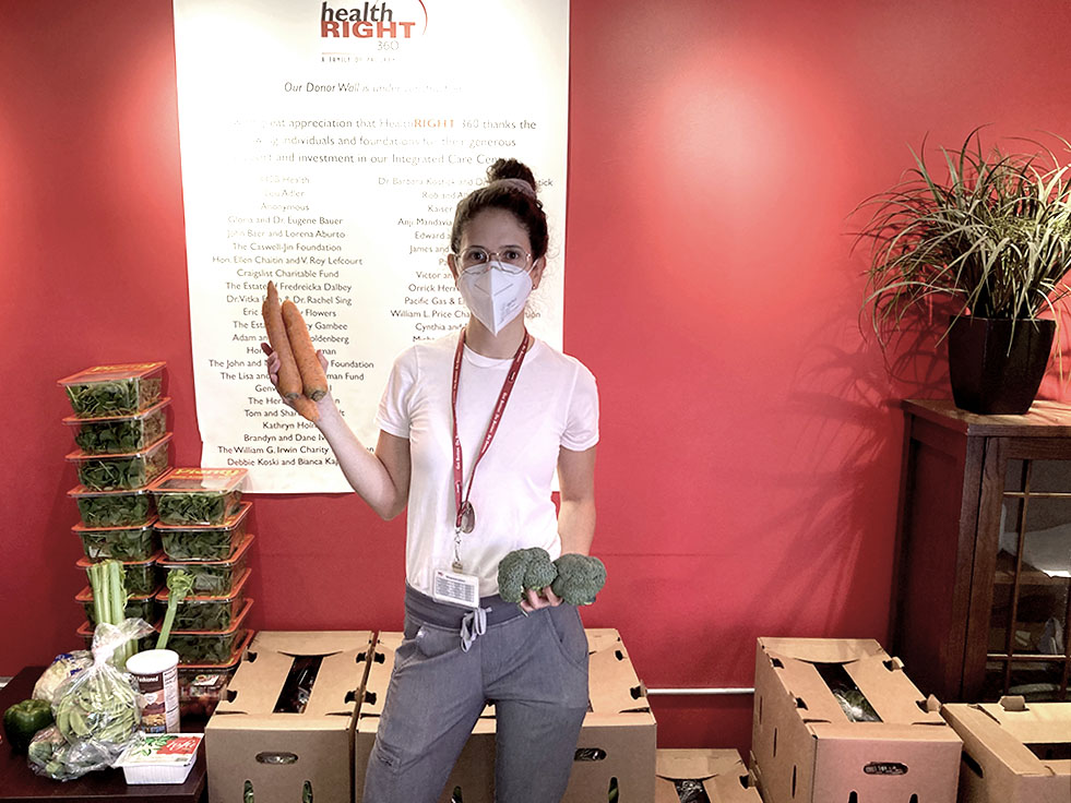 Mariana standing in front of boxes of fresh produce to give to patients.