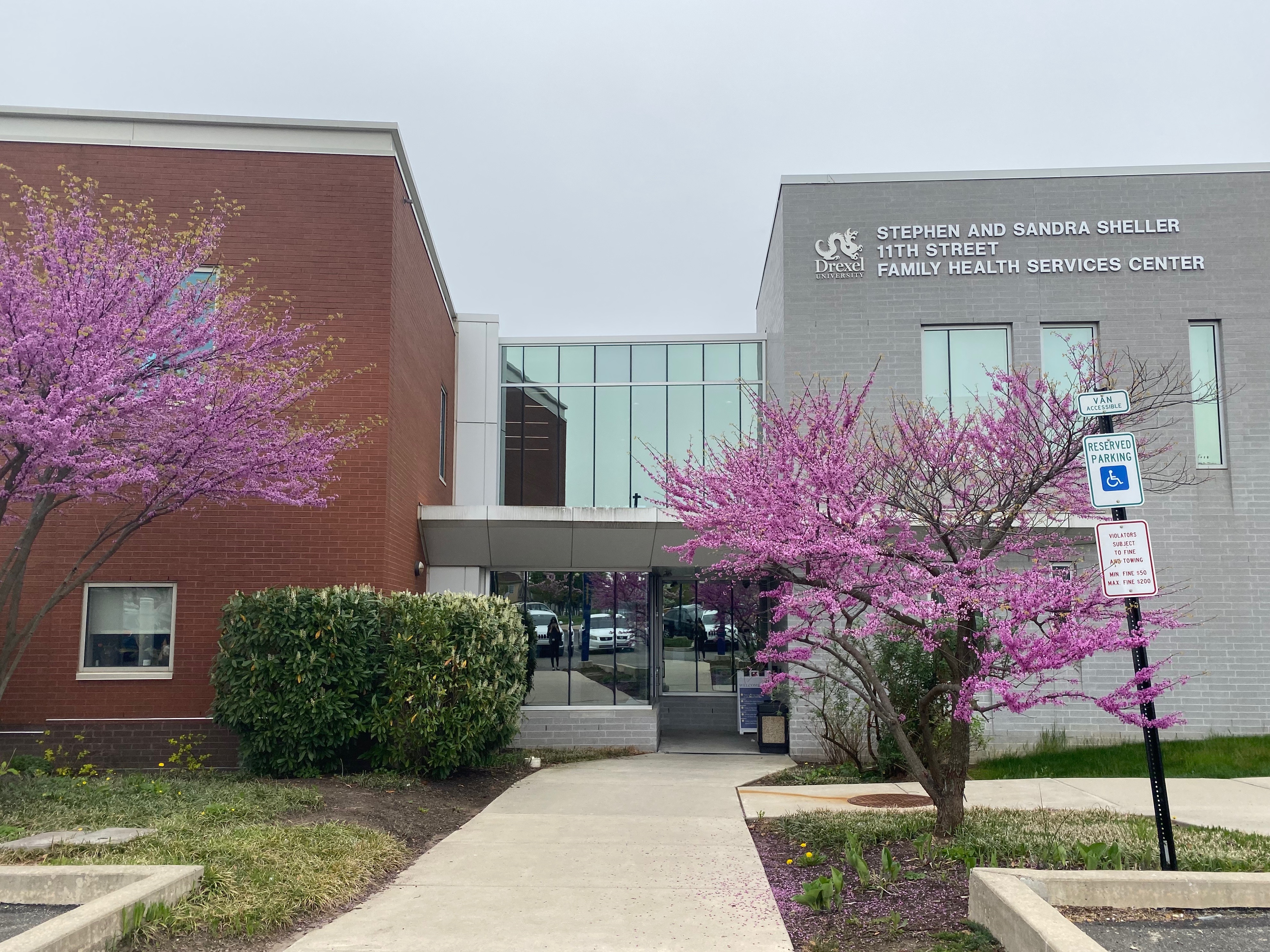 exterior of stephen and sandra sheller 11th street family health services with two pink trees blooming