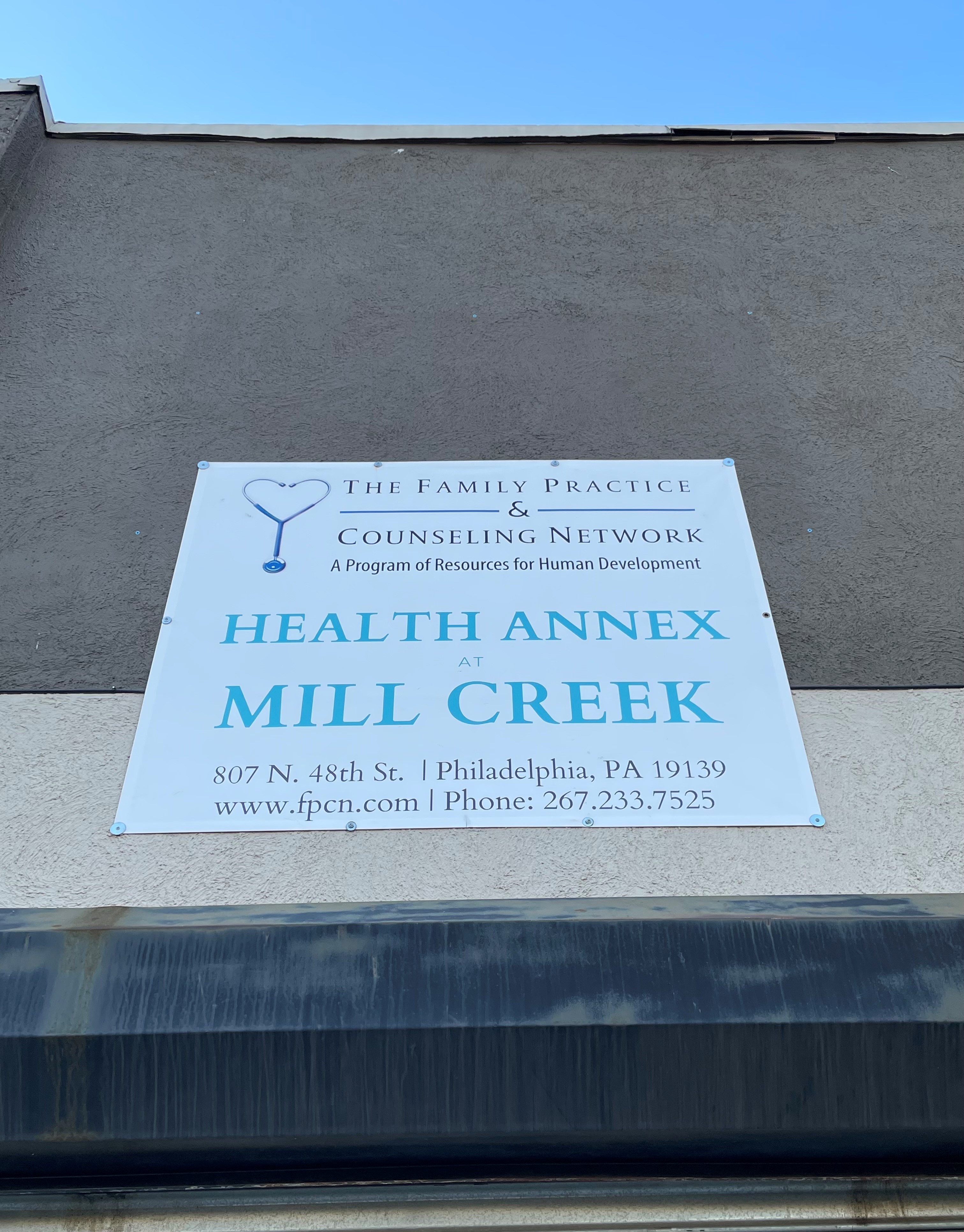 A sign having on a concrete wall that says "Health Annex at Mill Creek"