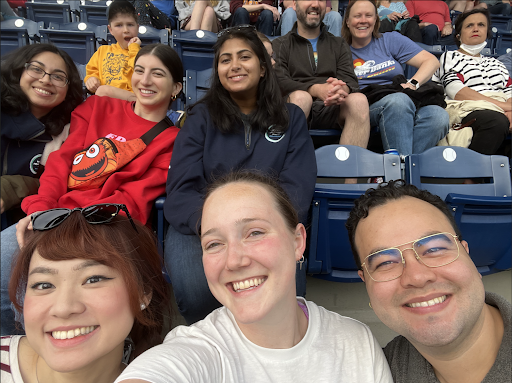 six smiling service members sitting in a baseball stadium