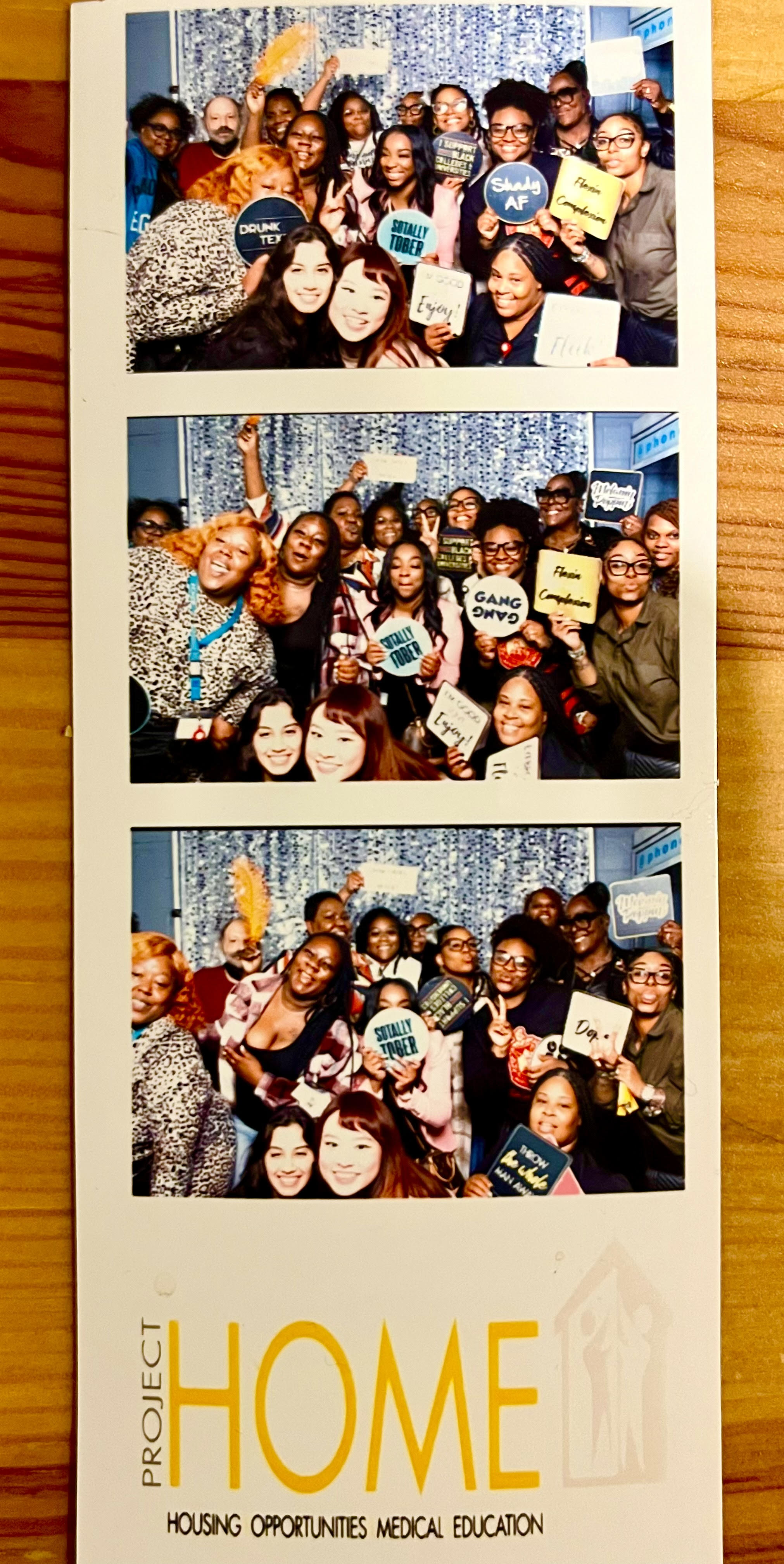 A series of three photos from a photobooth. In each photo there is a large group of people smiling and holding signs. The bottom of the series of photos says "Project Home Housing Opportunities Medical Education"