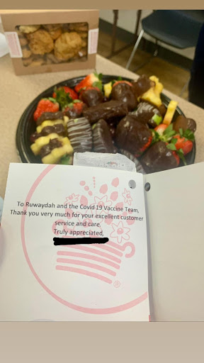 a tray of chocolate covered fruit with a card thanking the covid vaccine team