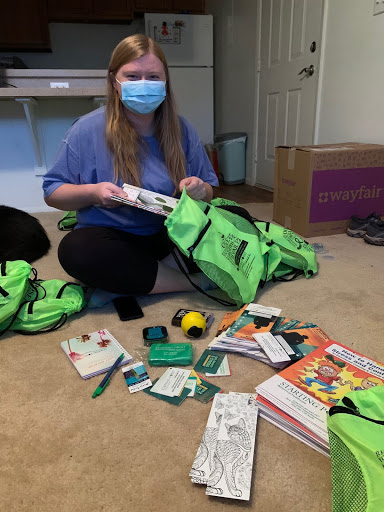 Paige sitting on the floor filling green bags to make wellness kits