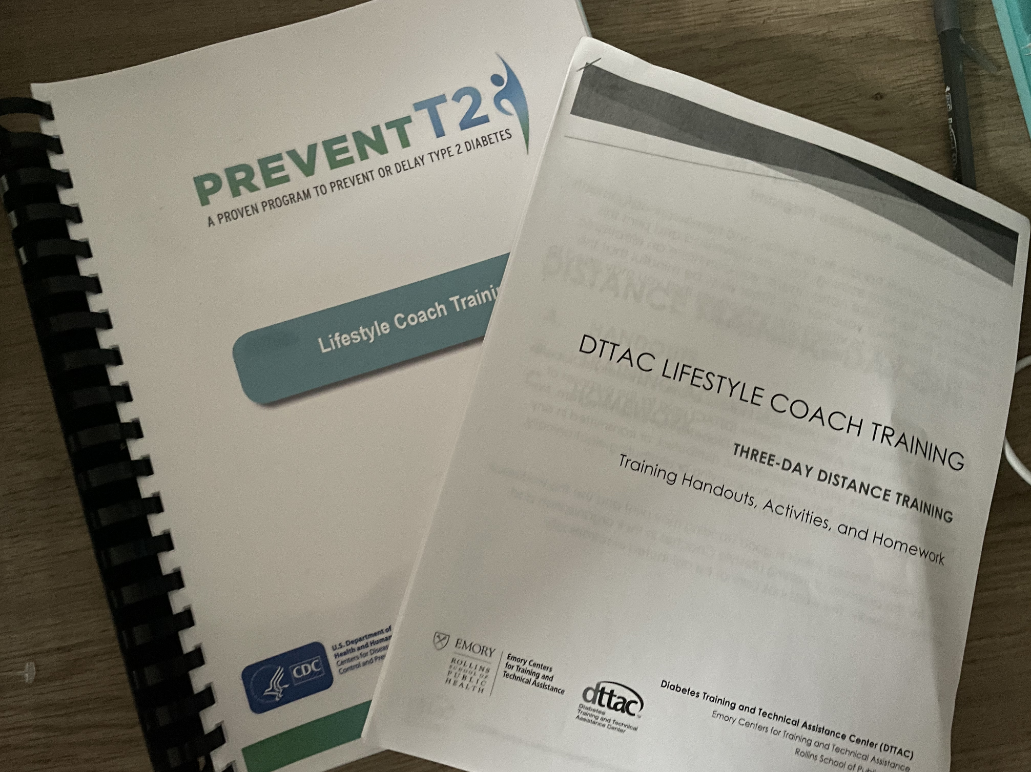 Two pamphlets sitting on a desk. The top one is called DTTAC Lifestyle coach training. The one under that is called Prevent T2: A proven program to prevent or delay type 2 diabetes